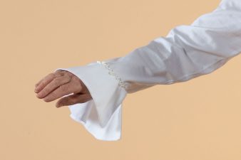 Valkoisen paitapuseron hiha, alaspäin levenevä ranneke, jossa kaunis helmikirjailu.