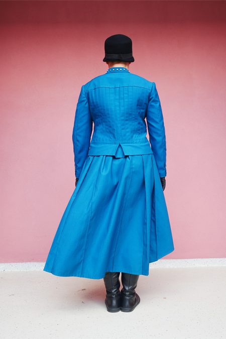 Kuva takaa, petroolinsineinen jakku ja laskoshame.