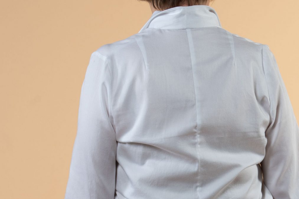 Lähikuvassa valkoinen paitapusero takaa, istuvat leikkaukset.