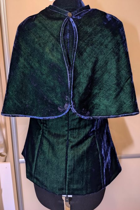 Kuva takaa, liivin päällä sinivihreä keeppi, valo heijastuu kauniisti.