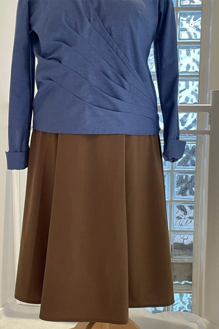 Lähikuva edestä, sinisen kietaisupaidan laskokset sekä ruskea hame.