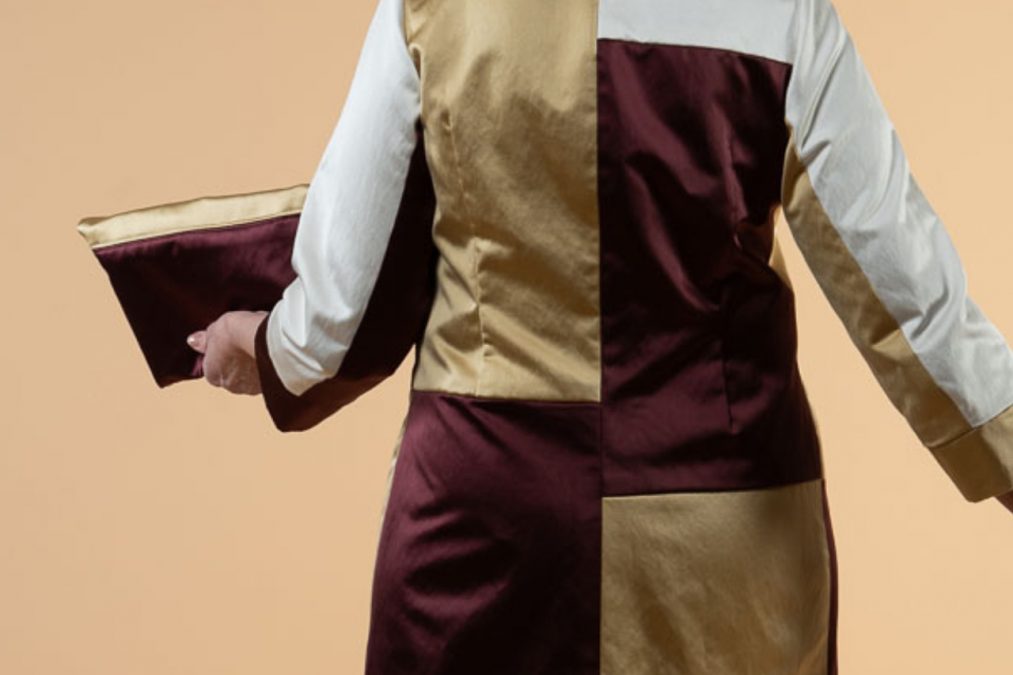 Juhlamekon selässä graafiset linjat, puuvillasatiinin väreinä kultaa, purppuraa ja valkoista.