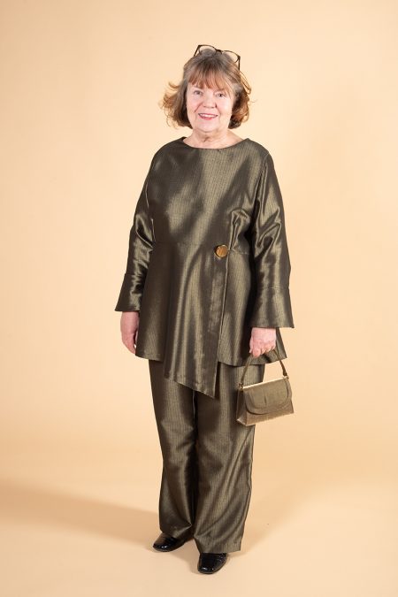 Kuva edestä, yhdistelmäasu himmeänhohtavaa vihreänsävyistä villakangasta, taidokkaat leikkaukset, pitkät trumpettihihat, leveät lahkeet.