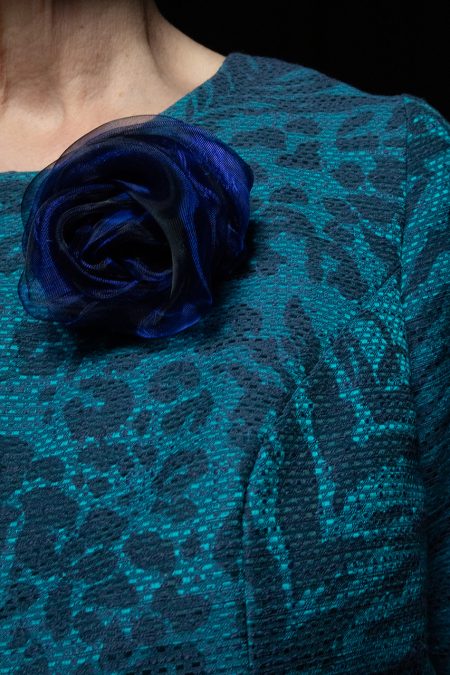 Lähikuva edestä, sinimusta kankainen ruusuke.