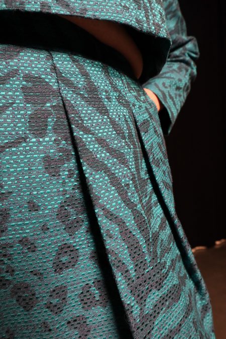 Lähikuva edestä, sinikuvioisen hameen laskokset, käsi taskussa.