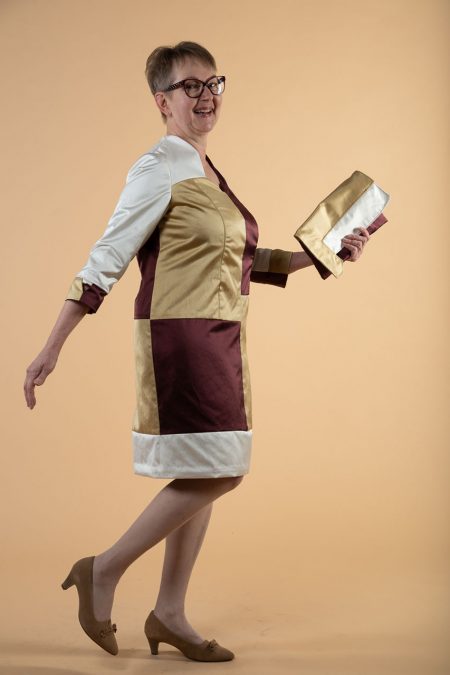 Kuva sivulta, juhlamekon väreinä kultaa, purppuraa ja valkoista, käsilaukku samoista kankaista.