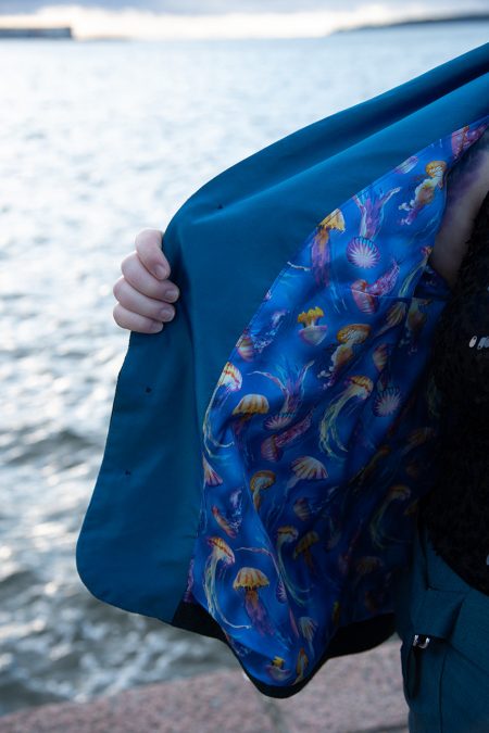 Lähikuva jakun vuorikankaasta, sinistä silkkiä meduusakuvioilla, taustalla meri.