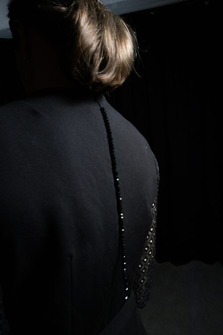 Lähikuva takaa, mustan haalarin vetoketjussa pitkä helmikoriste.