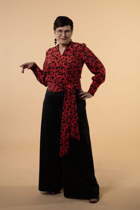 Kuva edestä, leveät housut mustaa laskeutuvaa villasekoitekangasta, yläosa puna-mustakuvioista kupron ja viskoosin sekoitetta.