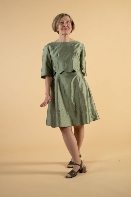 Kuva edestä, sammalenvihreä silkkimekko, jonka päällä piparkakkuhelmainen lyhyt pusero samasta kankaasta.