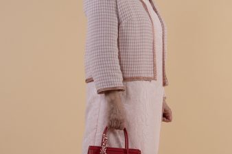 Lähikuvassa pikkuruudullinen Chanel-tyylinen jakku ja vaalea pinkki kotelomekko.