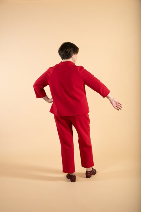 Kuva takaa, puserossa kolmeneljäsosa pituiset hihat ja tyylitelty kaulus, housut suoraa mallia.