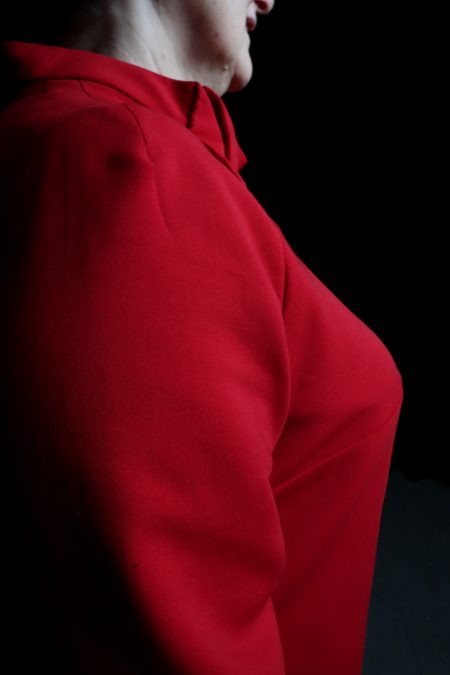 Lähikuvassa punaisen puseron sivuprofiili, istuvat leikkaukset.