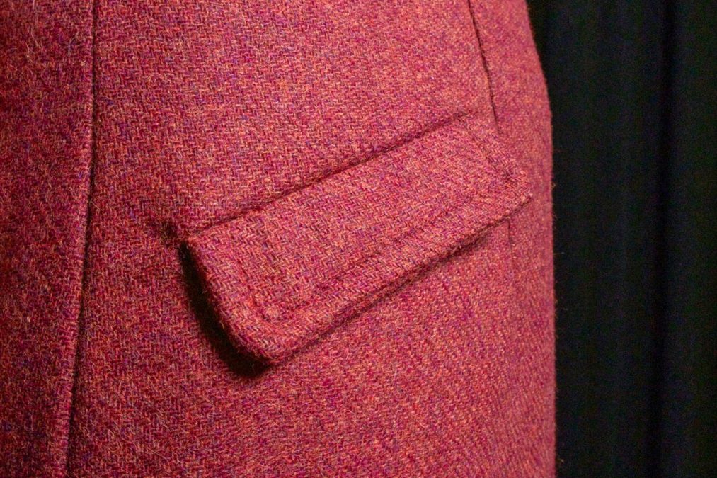 Lähikuvassa viininpunaisen villakangasmekon taskun kansi.