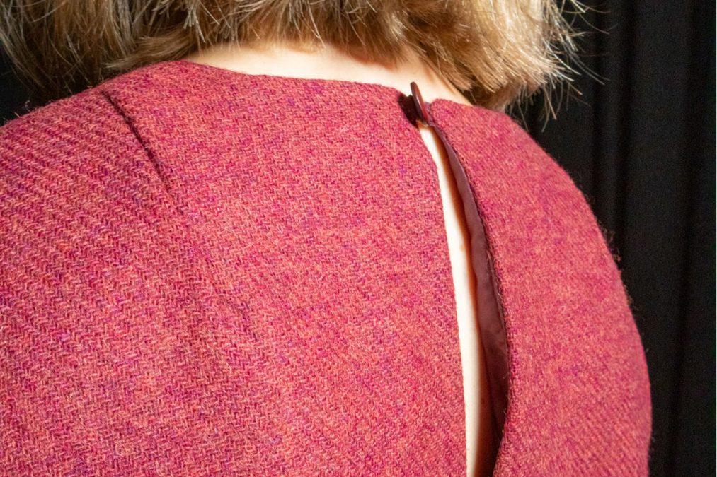 Lähikuvassa viininpunaisen kotelomekon selkää, pääntien pitkä halkio ja nappikiinnitys.