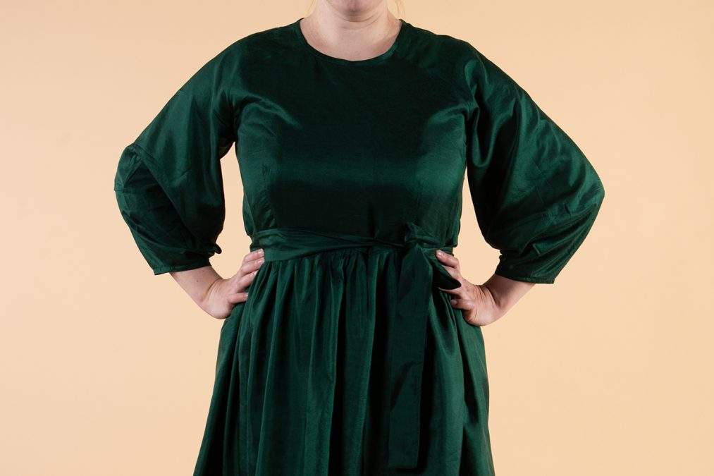 Lähikuva edestä, vihreän silkkimekon lyhdyn muotoiset raglanhihat, pyöreä pääntie, samasta kankaasta vyö.