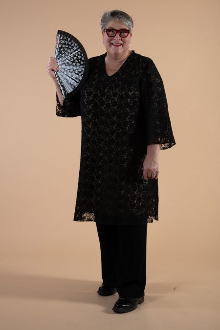 Kuva edestä, musta pitsitunika kolmeneljäsosa pituisilla hihoilla, kädessä viuhka.