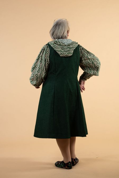 Kuva takaa, metsänvihreä liivimekko, puserossa runsaat hihat, korkeat rannekkeet ja huppu.
