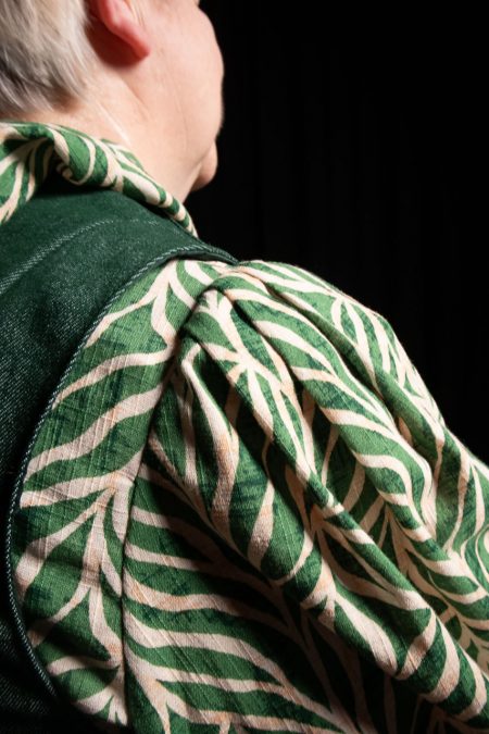 Lähikuvassa puseron vihreä lehtikuvio, hihan runsas laskostus kädentiellä.