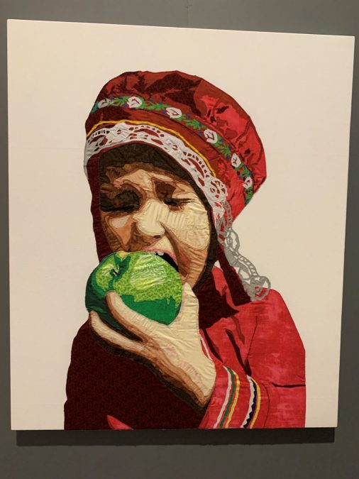 Lapin asuun pukeutunut tyttö haukkaa vihreää omenaa. Tilkkuaplikaatio.