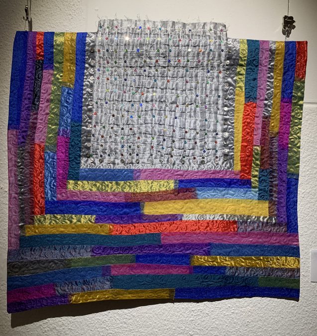 Vahvoilla väreillä kaitaleista toteutettu tilkkutyö.